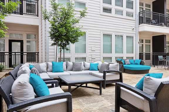 A patio with a sofa set and a tree.