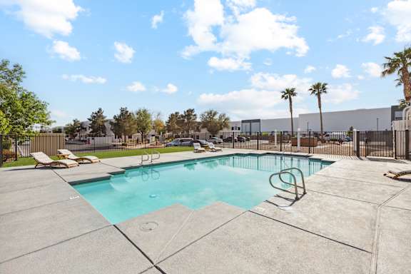 A swimming pool surrounded by a concrete patio and palm trees.