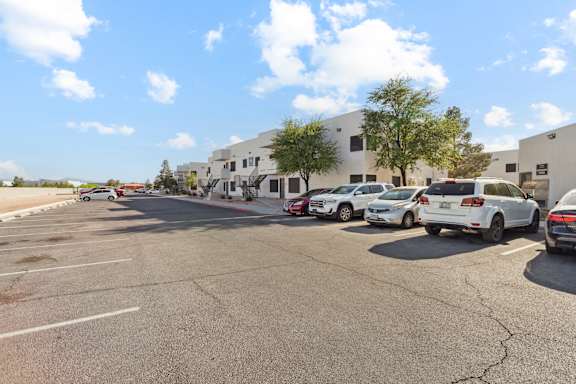 A parking lot with several cars parked in front of a building.