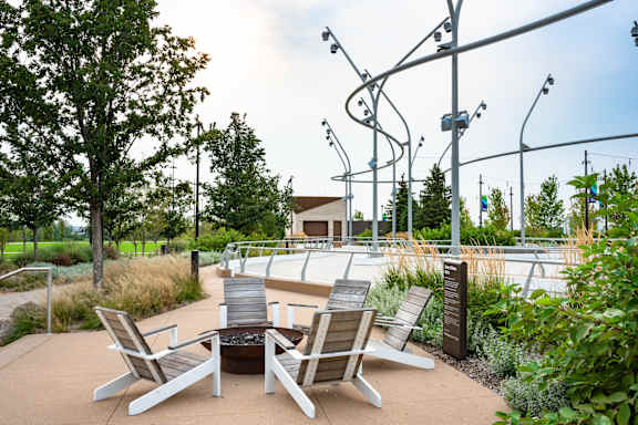 A patio with chairs and a table is surrounded by trees.