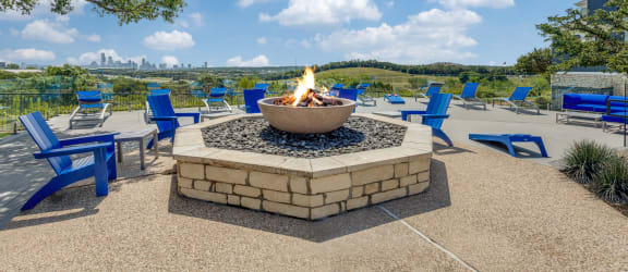a fire pit with blue chairs and a view of the city