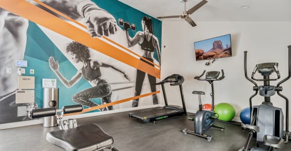 a gym with cardio equipment and a large mural on the wall