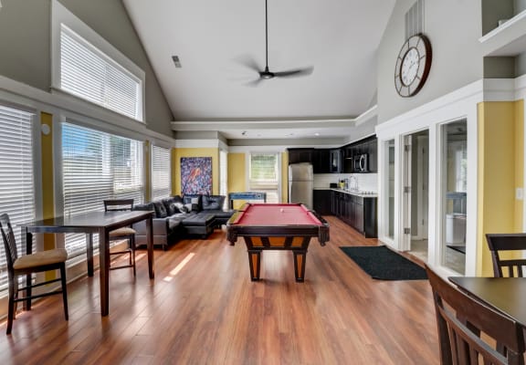 a large living room with a pool table and a kitchen in the background