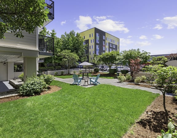 a backyard with green grass and a patio with a table and chairs  at King Arthurs Court, Seattle, Washington