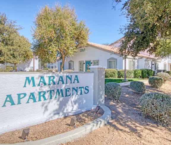 a sign that says marana apartments with trees in the background