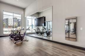 A gym with a mirror, treadmill, and exercise bike.