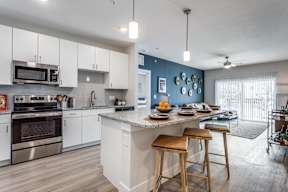 A kitchen with white cabinets and a blue wall.