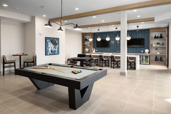 a clubhouse with a pool table and a bar with a tv