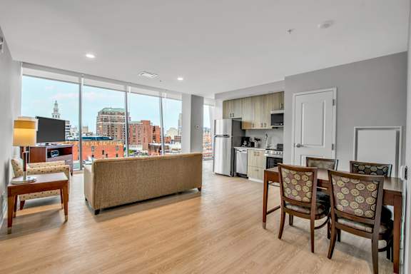 A living room with a couch, chairs, and a view of the city.