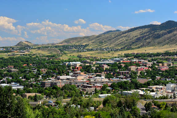 A cityscape with buildings and greenery under a blue sky with clouds.