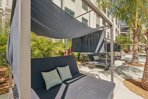 A grey couch with two pillows under a grey canopy at The Stadler Luxury Apartments, Bradenton
