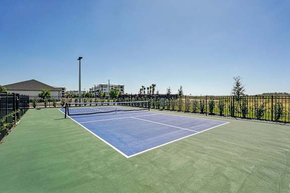 A tennis court with a net and a green surface at The Stadler Luxury Apartments, Bradenton, FL