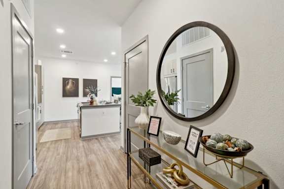 a living room with an oval mirror and a glass display case at The Depot Luxury Apartment Homes, Raymore, 64083