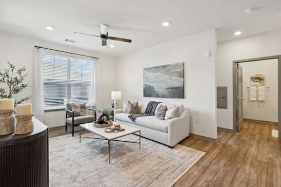 a living room with a white couch and a coffee table at The Depot Luxury Apartment Homes, Raymore, 64083
