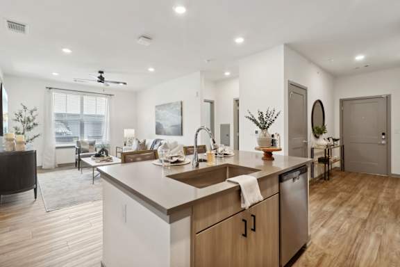 a kitchen with an island and a living room with a couch at The Depot Luxury Apartment Homes, Raymore, 64083