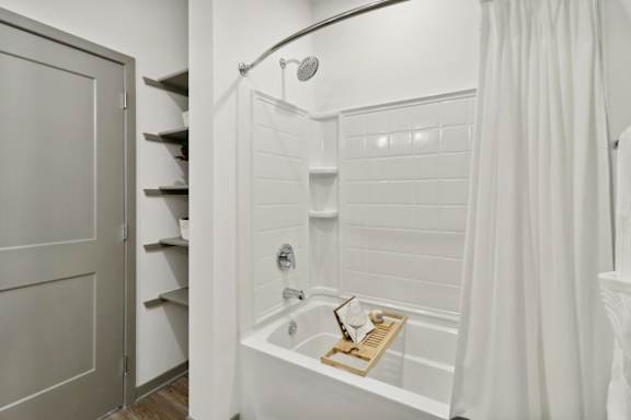 a bathroom with a shower and a tub and a closet at The Depot Luxury Apartment Homes, Raymore, 64083