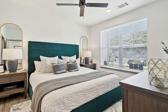 a bedroom with a large bed and a ceiling fan at The Depot Luxury Apartment Homes, Raymore, 64083