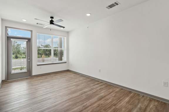 a living room with white walls and a window and a ceiling fan at The Depot Luxury Apartment Homes, Raymore, 64083