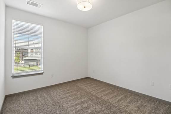 the living room of an apartment with carpet and a window at The Depot Luxury Apartment Homes, Raymore, 64083
