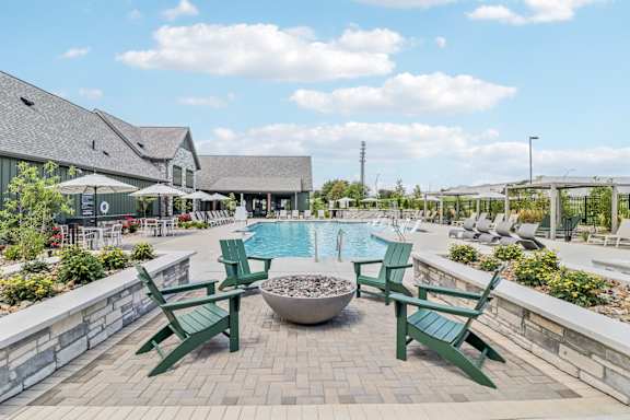 a swimming pool with green chairs and a fire pit at The Depot Luxury Apartment Homes, Raymore, MO