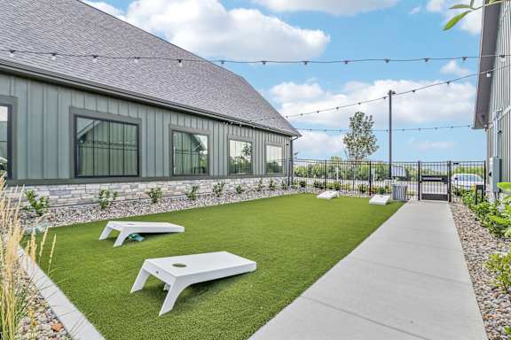the backyard of a house with a lawn and picnic tables at The Depot Luxury Apartment Homes, Raymore, MO