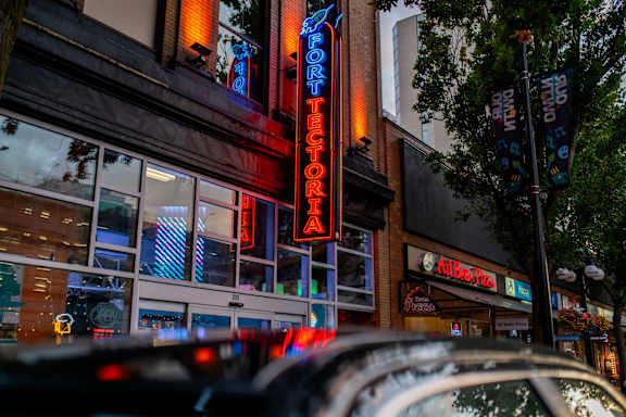 A neon sign that says "Fort Tectoria" is lit up in red and blue over a restaurant entrance.