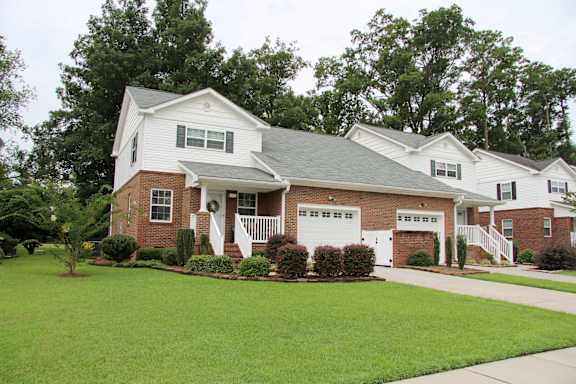 A white house with a grey roof and a brick chimney.