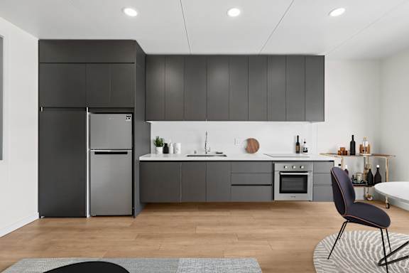 A modern kitchen with a black fridge and a black chair.