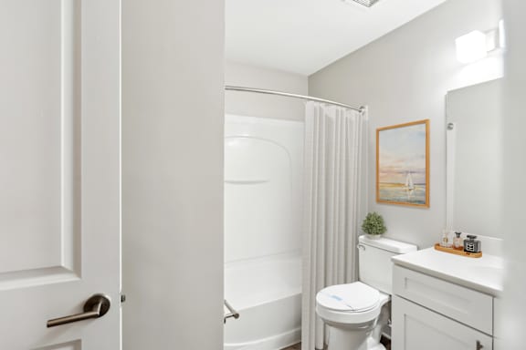 A white bathroom with a toilet, sink, and shower.