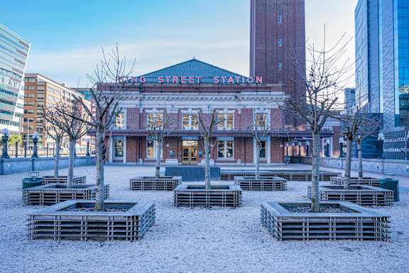 a city square in front of a building with benches in the snow