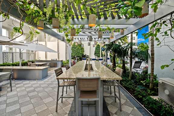  A patio with a table and chairs under a canopy of green plants.