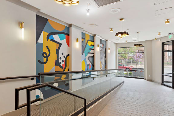 a large colorful painting hangs on the wall at the top of a staircase in a building  at The Griffin Royal Oak, Royal Oak, Michigan
