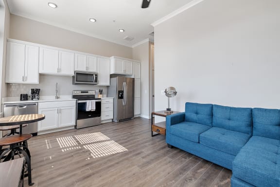 a living room with a blue couch and a kitchen with a stove and refrigerator