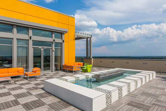 A modern building with a glass balcony and orange umbrellas.
