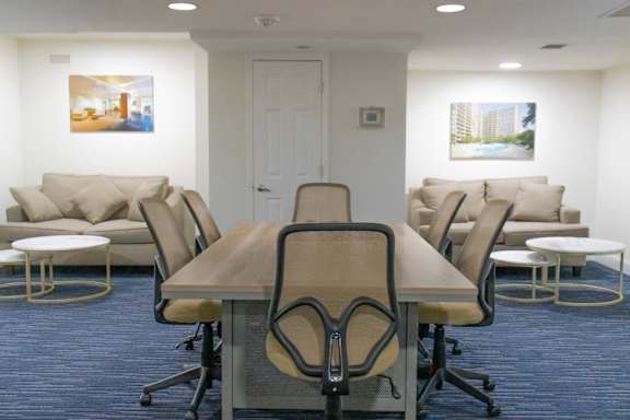 A conference room with a long table surrounded by chairs.