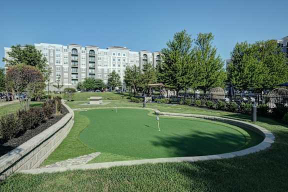 A golf course is located in front of apartment buildings.