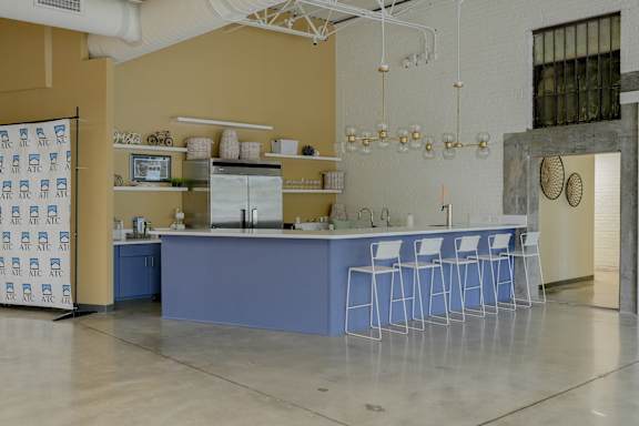 A blue bar with white stools in a room with a yellow wall.