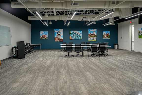 A room with a long table and chairs, a podium, and paintings on the wall.