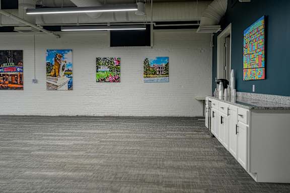 A room with a white wall and a grey carpet.