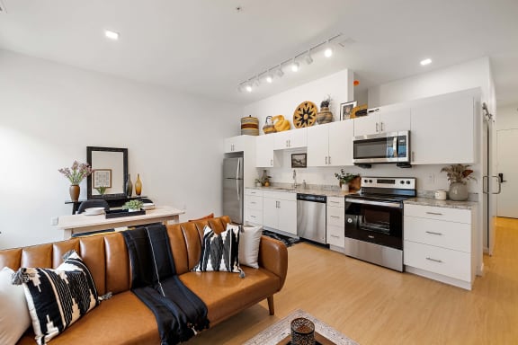 a living room with a leather couch and a kitchen with a stove at The Freelon at Sugar Hill, Detroit, MI 48201