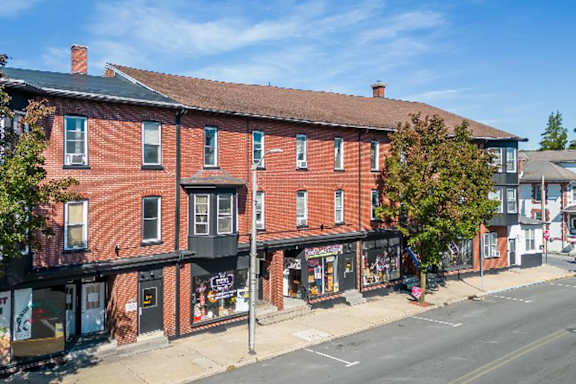 A red brick building with a black awning on the corner of a street.