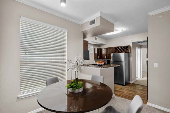 a dining room with a table and chairs and a kitchen with a refrigerator