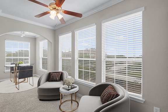 a living room with large windows and a ceiling fan