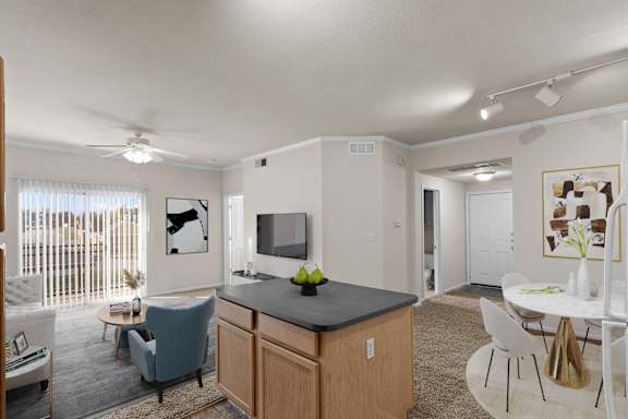 A well-lit kitchen and living room with modern furniture.