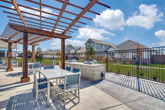 A patio with a table and chairs under a wooden pergola.