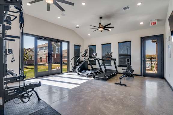 A spacious home gym with a treadmill, elliptical machines, and a weight bench.
