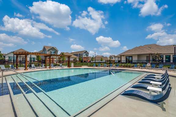 A large outdoor swimming pool with loungers and a clear blue sky.
