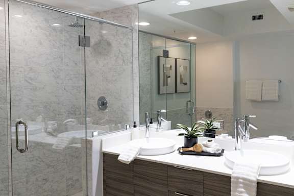 A modern bathroom with two sinks and a walk-in shower.