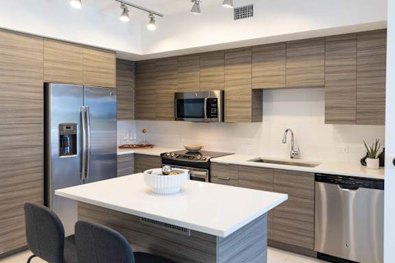 A modern kitchen with a white countertop and a stainless steel refrigerator.