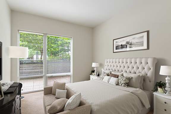 A bedroom with a large bed and a window overlooking a tree-filled area.